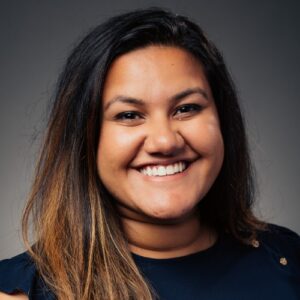 close-up shot of EMPH student Trishna Singh wearing a black sweater standing against a grey background indoors