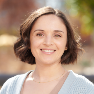 close up photo of Maite Medina standing outdoors; chin length brown hair and light blue cardigan sweater